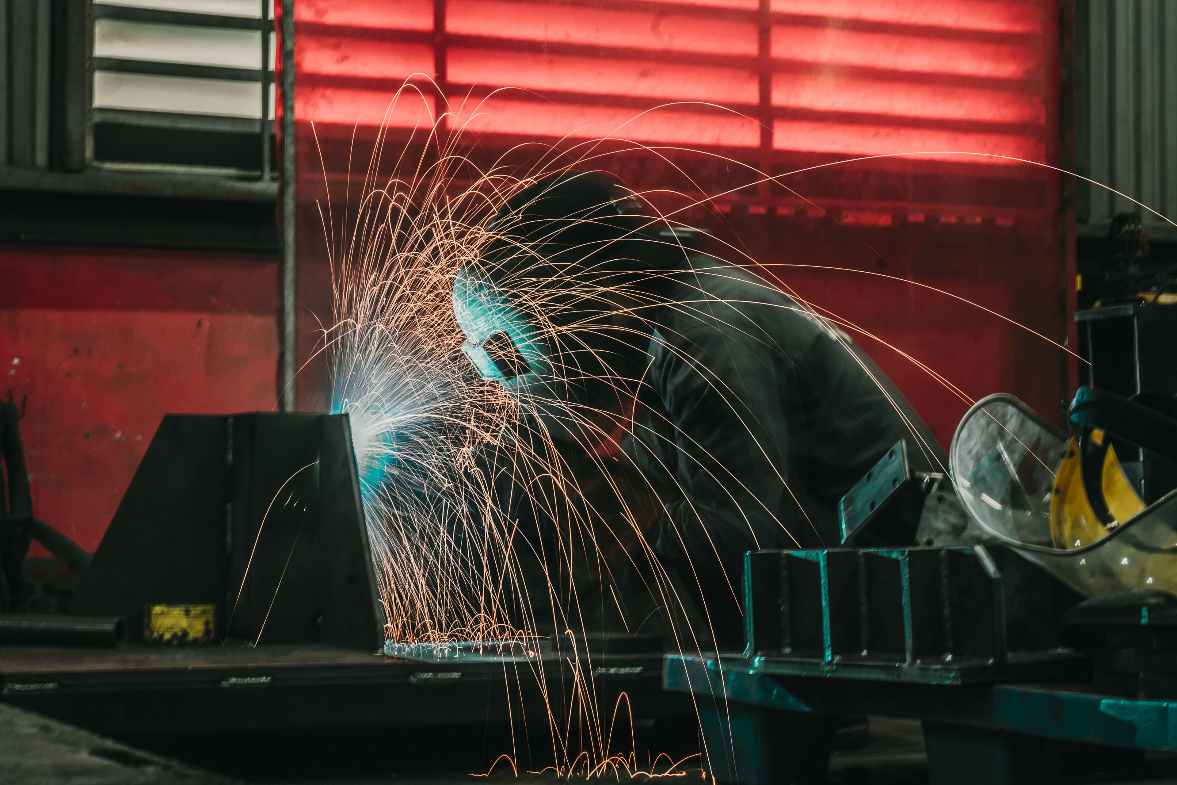 Welder working on metal fabrication in an industrial workshop